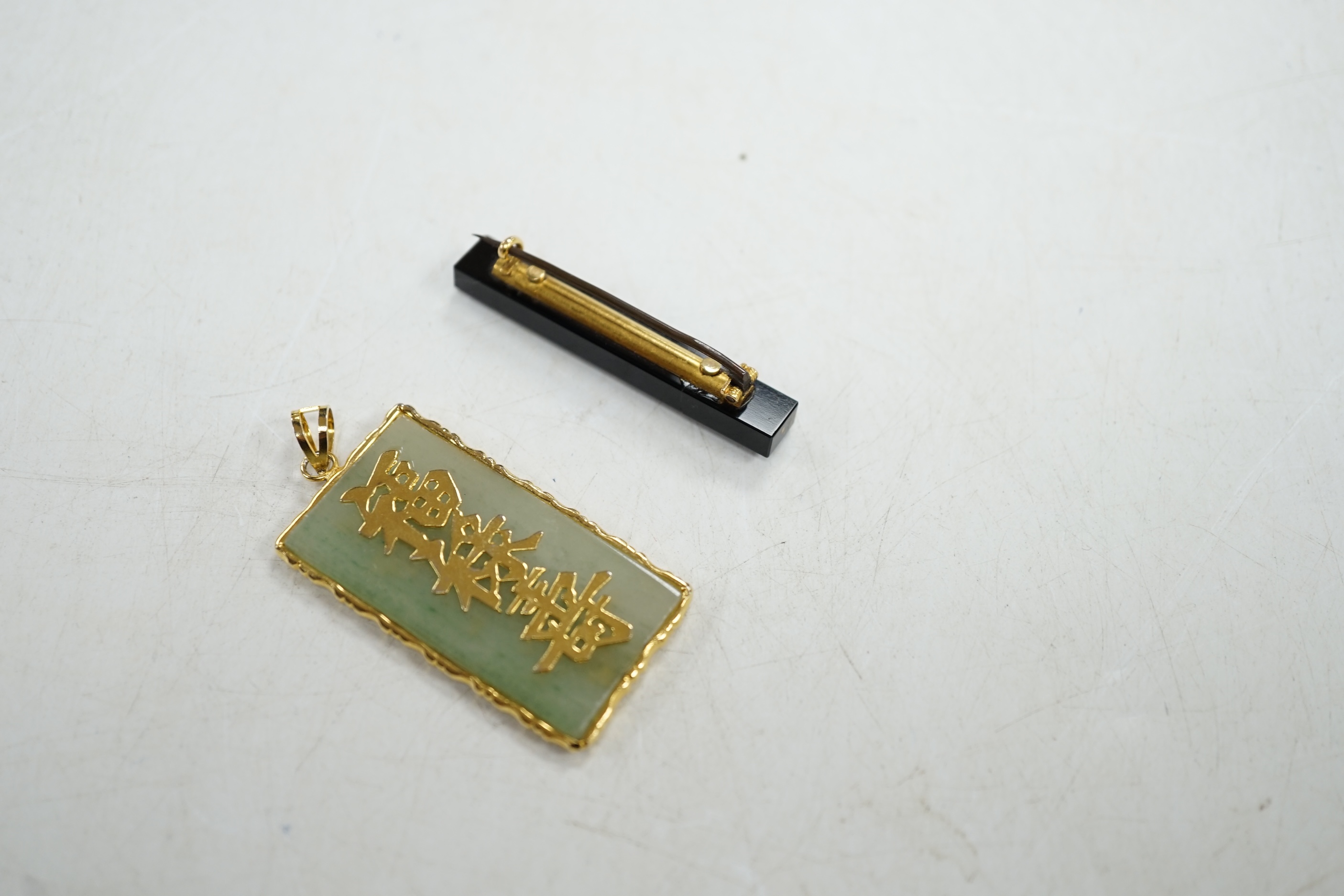 A late Victorian gold mounted black onyx and pearl bar brooch, and a Chinese yellow metal mounted jadeite pendant. Condition - fair